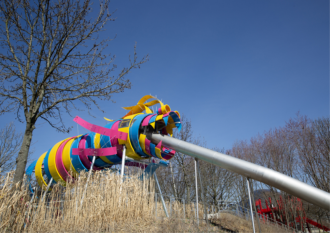 Photo du jardin du Dragon au Parc de la Villette à Paris avec structure de dragon colorée et aire de jeux pour enfants.