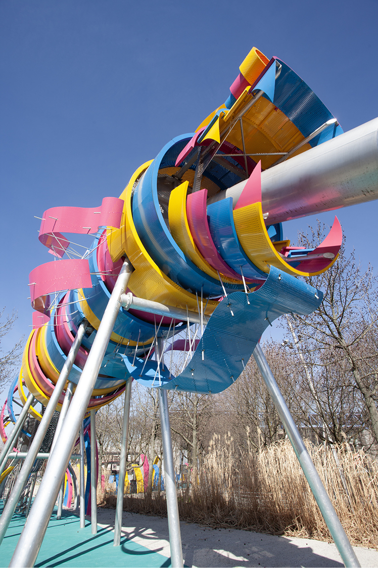 Photo du jardin du Dragon au Parc de la Villette à Paris avec structure de dragon colorée et aire de jeux pour enfants.